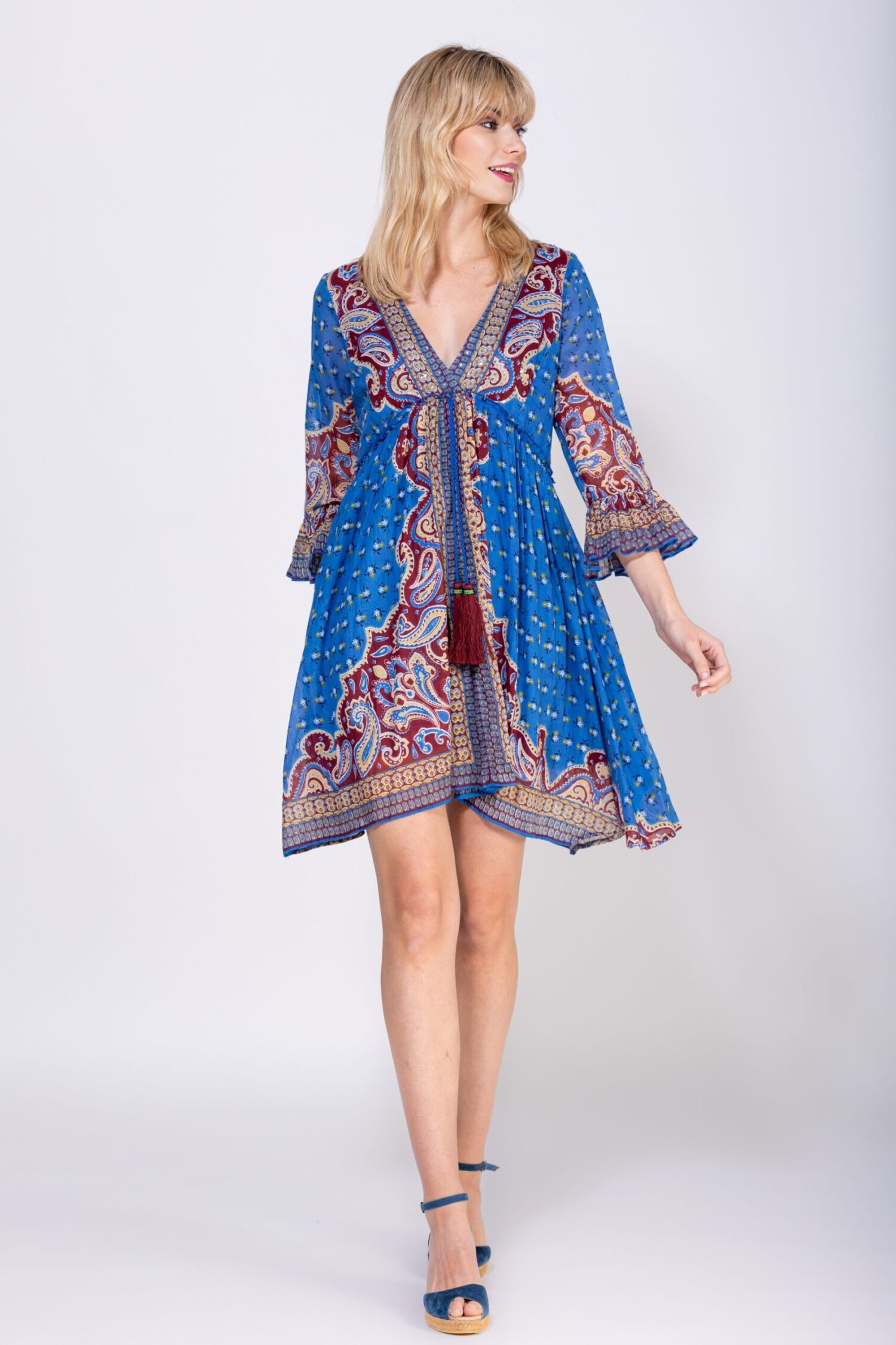 VESTIDO CORTO ESTAMPADO CACHEMIRE, ESCOTE EN V CON MANGAS 3/4 ACABADAS EN VOLANTE EN BOCAMANGA, CORTE BAJO PECHO CON CORDON ACABADO EN BORLA CON DETALLES DE ABALORIOS, FALDA CON MUCHO VUELO Y ACABADA EN ESTAMPADO CON BORDE