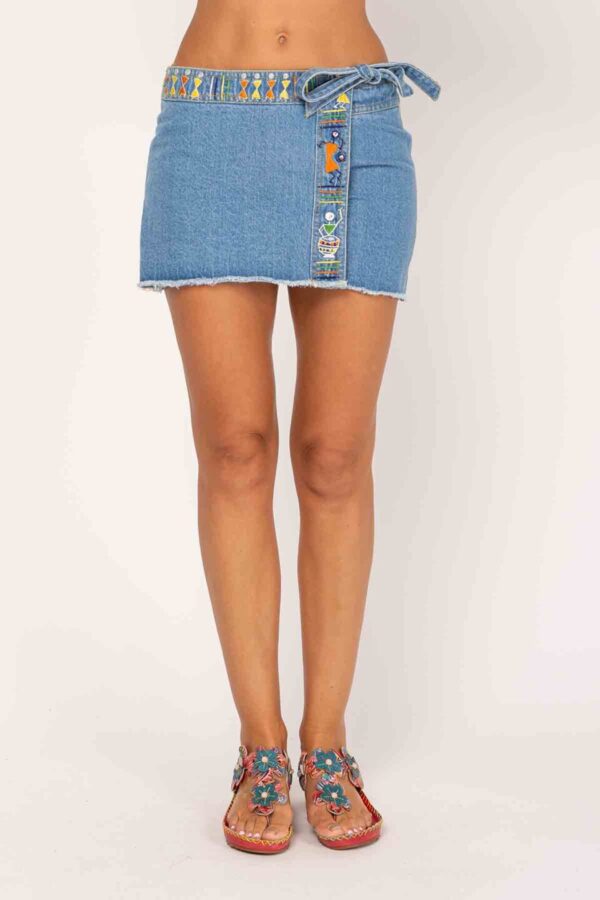 FALDA PANTALON JEAN, CIERRE CRUZADO LATERAL CON LAZO, DETALLE DE BORDADO EN CINTURILLA Y RIBETE FRONTAL, BAJO DESILACHADO. DOS BOLSILLOS TRASEROS CON DETALLE BORDADO EN UNO DE ELLOS